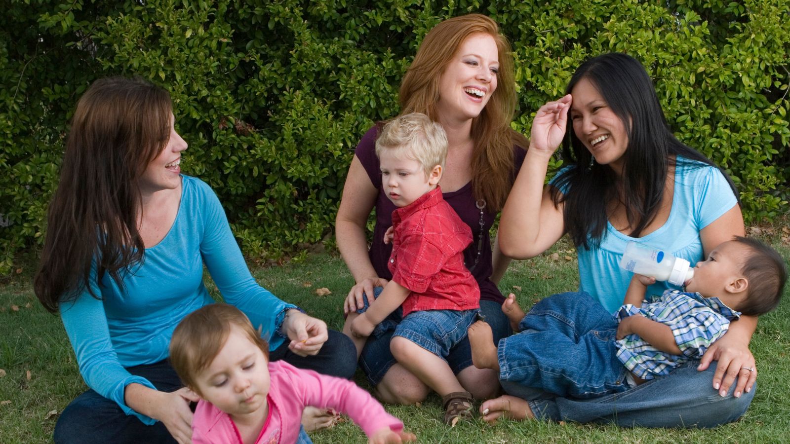Müttern mit Kindern auf einer Wiese sitzend